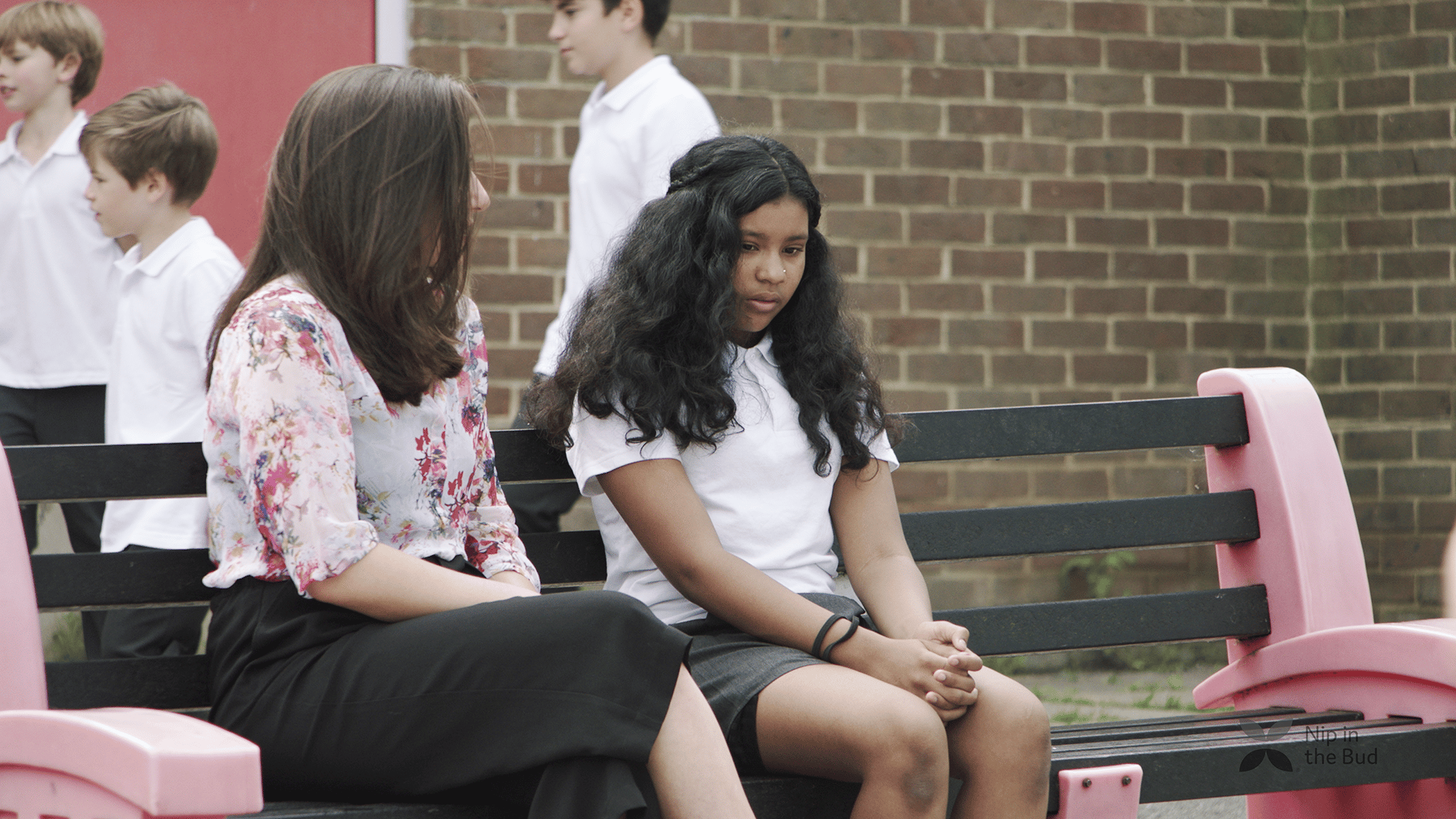 A teacher talks to a girl in the playground.