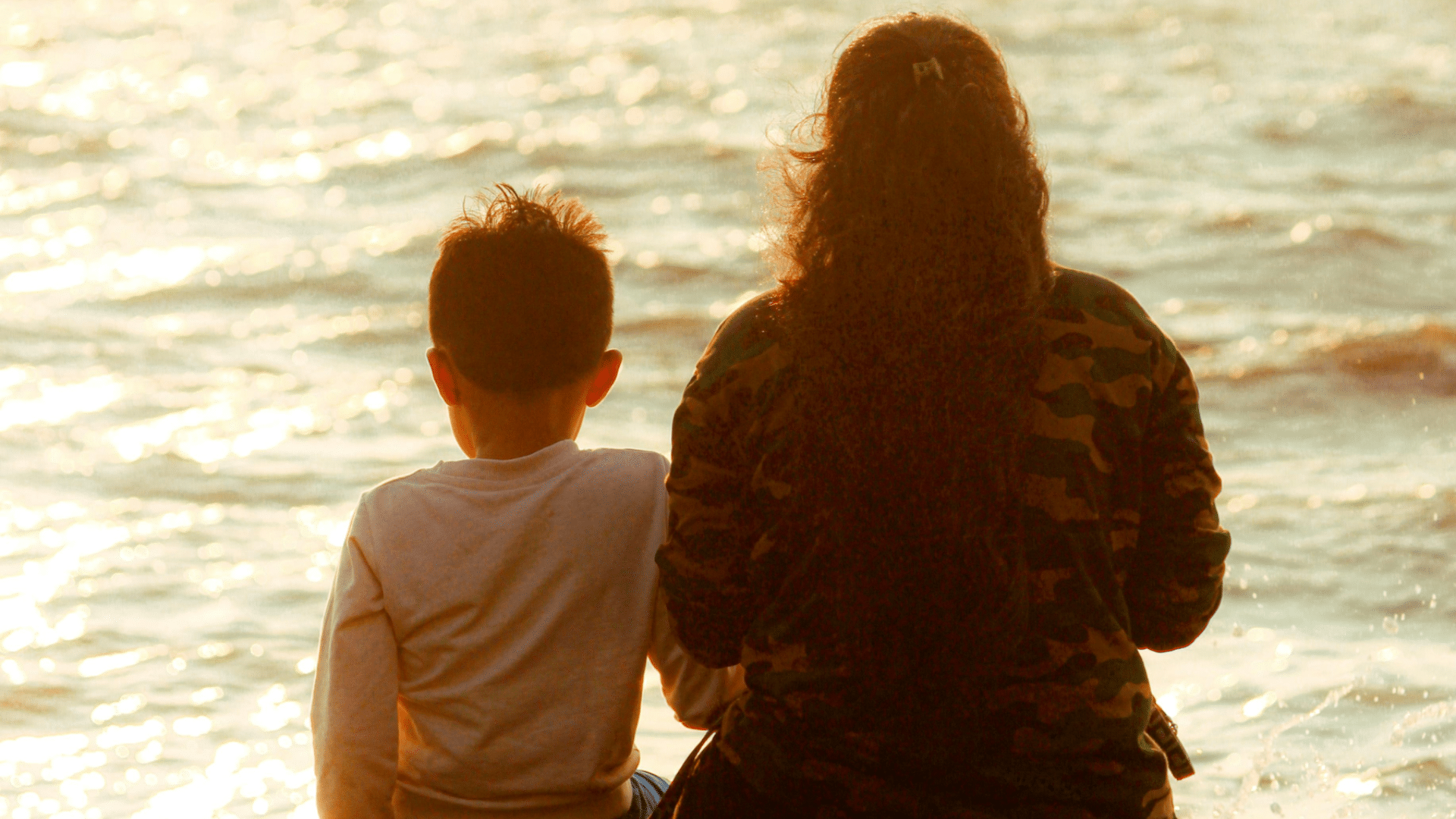 woman and child seen from behind looking out to sea
