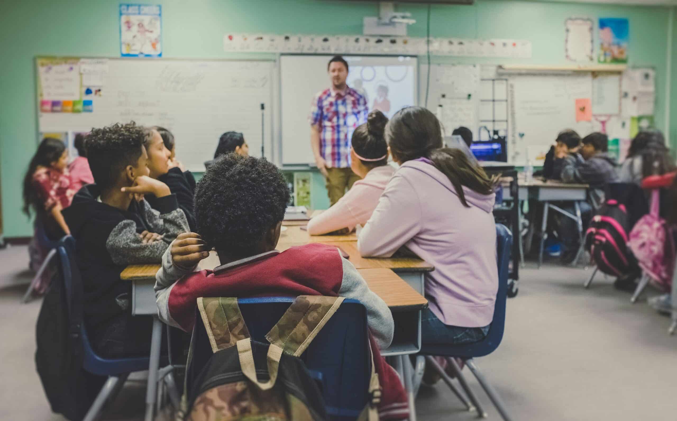 children looking at a whiteboard in classroom from behind